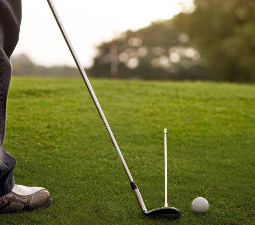 Golfer practicing chip shot with club white alignment rod next to ball on green for golf alignment rods sale