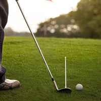 Golfer practicing chip shot with club white alignment rod next to ball on green for golf alignment rods sale