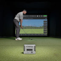 Golf indoor simulator setup with man swinging and FlightScope Mevo Plus launch monitor on turf