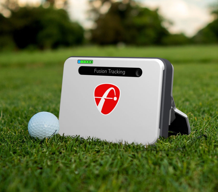 FlightScope Mevo Plus launch monitor on grass next to golf ball with Fusion Tracking logo