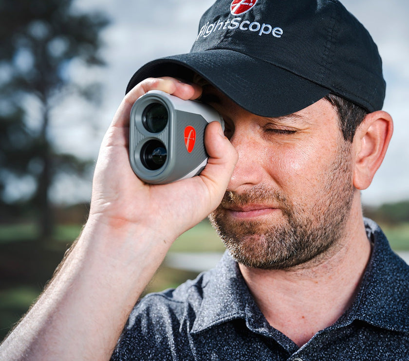 A golfer using the FlightScope i4 Golf Rangefinder on the course for accurate distance measurements