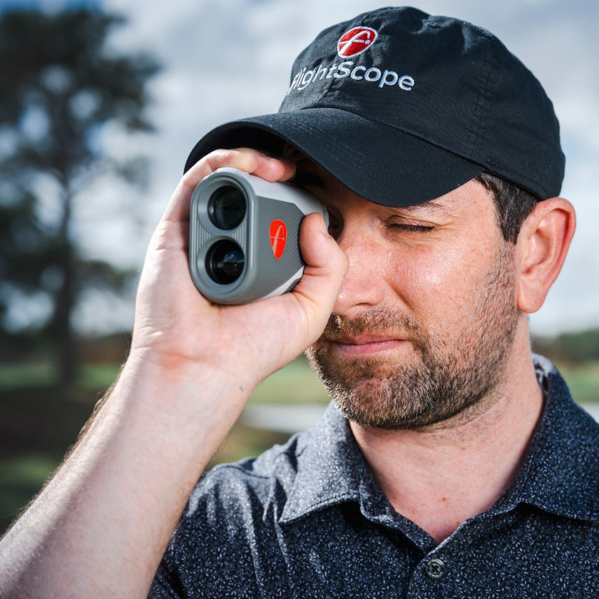A golfer using the FlightScope i4 Golf Rangefinder on the course for accurate distance measurements