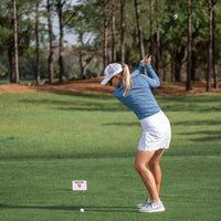 Golf course scene with a female golfer using the FlightScope Mevo+ launch monitor for swing analysis.