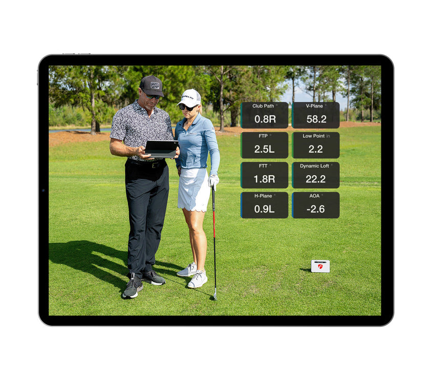 FlightScope Golf app on tablet showing coach instructing golfer with swing data overlays premium golf training equipment