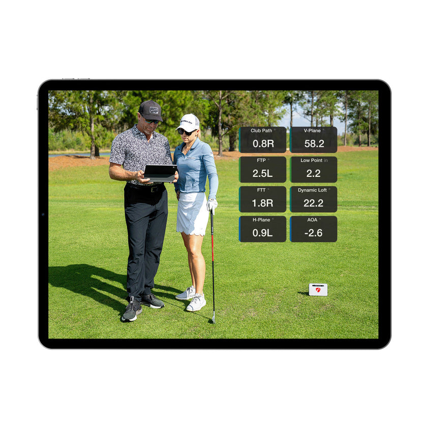 FlightScope Golf app on tablet showing coach instructing golfer with swing data overlays premium golf training equipment