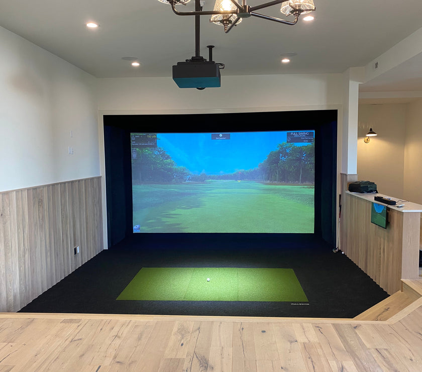 Full Swing Golf indoor setup with ceiling projector hitting mat and impact screen showing course home golf simulator package