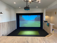 Full Swing Golf indoor setup with ceiling projector hitting mat and impact screen showing course home golf simulator package