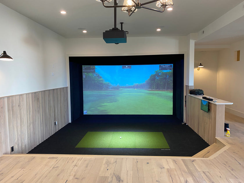 Full Swing Golf indoor setup with ceiling projector hitting mat and impact screen showing course home golf simulator package