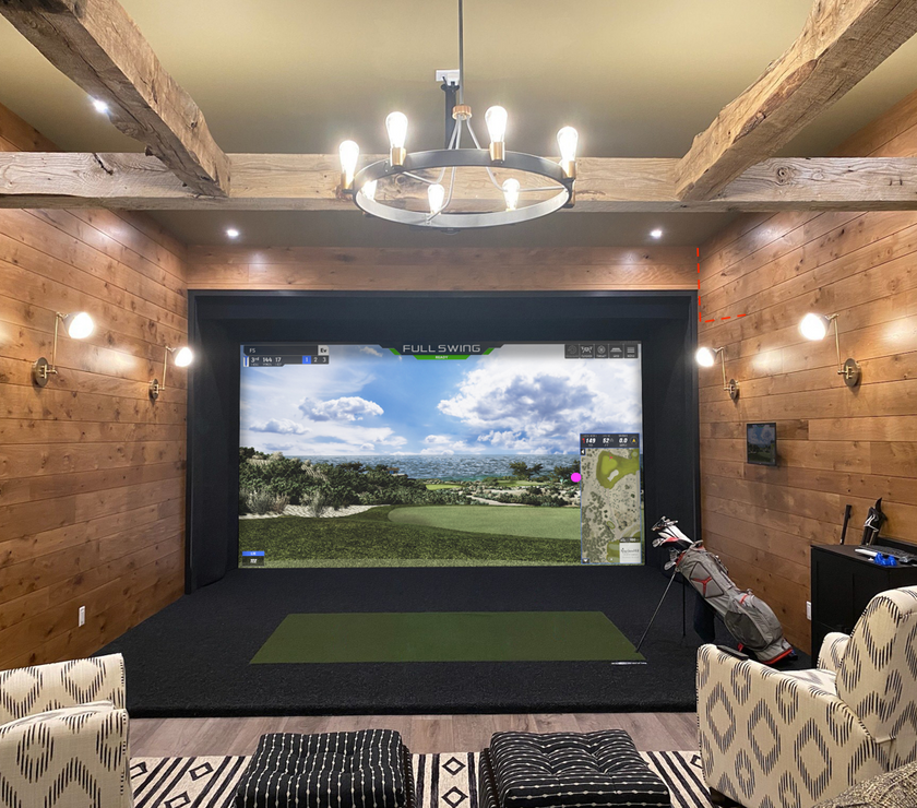 Full Swing Golf home golf simulator package in a wood paneled room with impact screen turf mat and seating