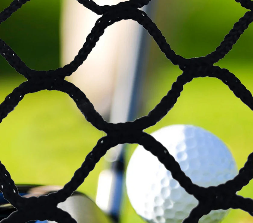 Close-up of black high impact golf practice netting with a golf ball and club in the background on green grass