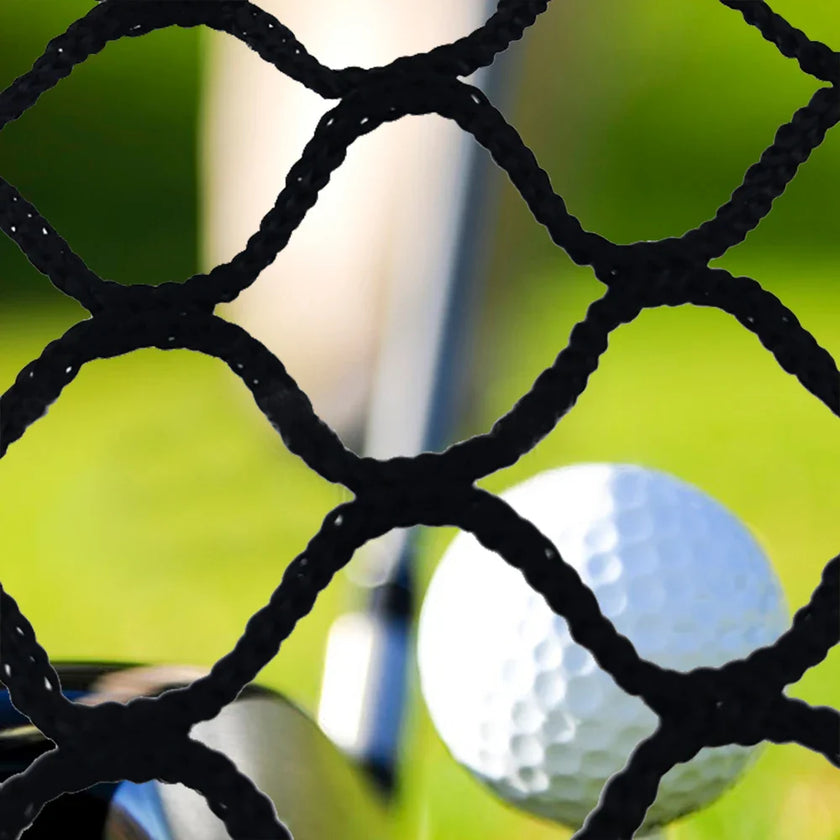 Close-up of black high impact golf practice netting with a golf ball and club in the background on green grass