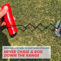 Hand holding red handle of Speed Trap swing trainer with black coiled tether attached to practice rod on grass