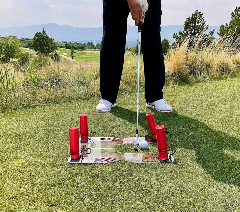 Golfer using Speed Trap swing trainer on golf course turf with putter and golf ball near mirrored alignment base