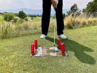 Golfer using Speed Trap swing trainer on golf course turf with putter and golf ball near mirrored alignment base