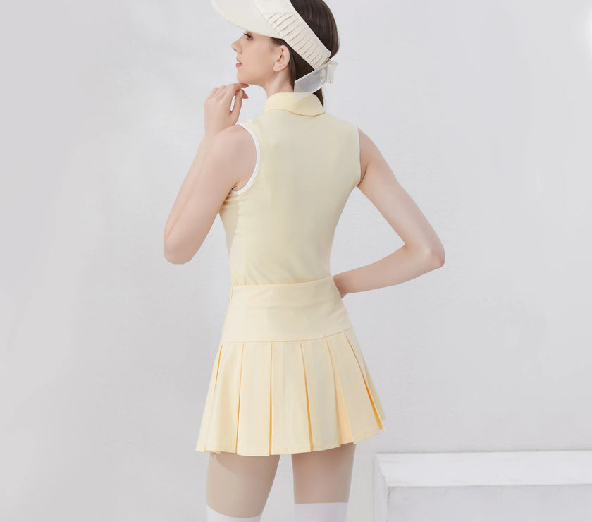 Stylish women's golf polo shirt in soft yellow paired with a pleated skirt and visor for a chic sporty look