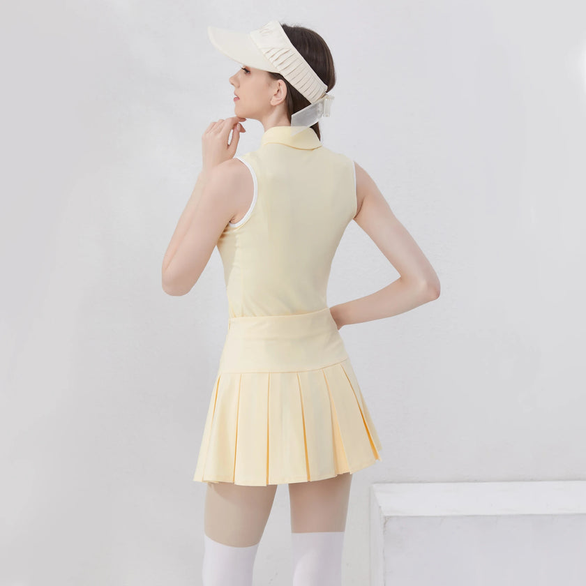 Stylish women's golf polo shirt in soft yellow paired with a pleated skirt and visor for a chic sporty look